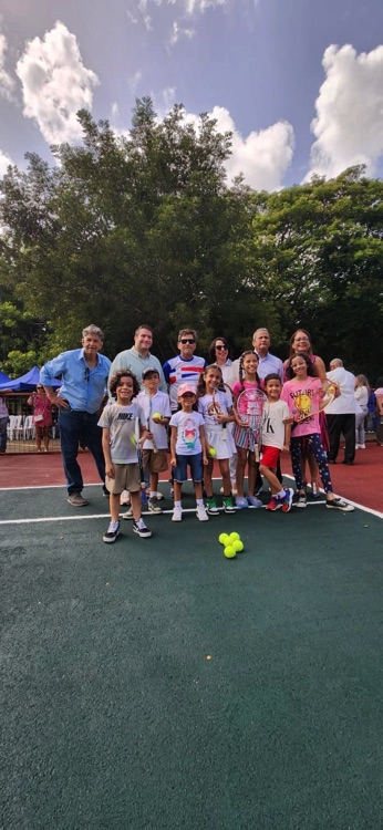 Grupo de participantes reunidos con raquetas y pelotas en la cancha.