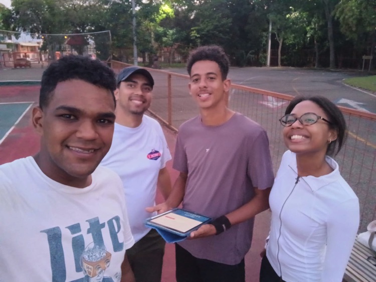 Cuatro participantes posan con una placa en una cancha de tenis.