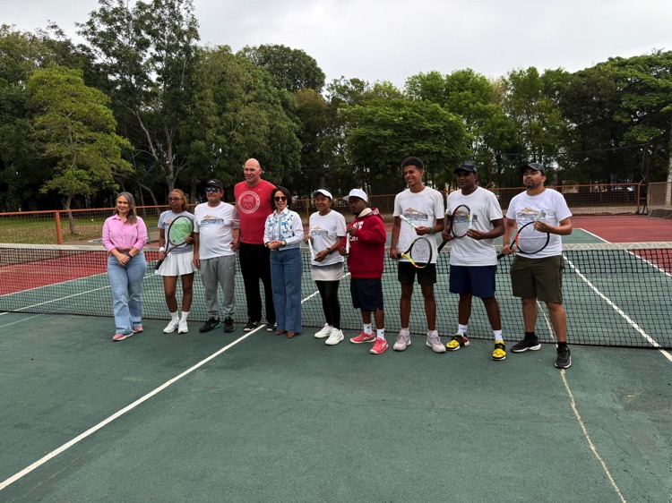 Grupo de participantes posa junto a la red de tenis.