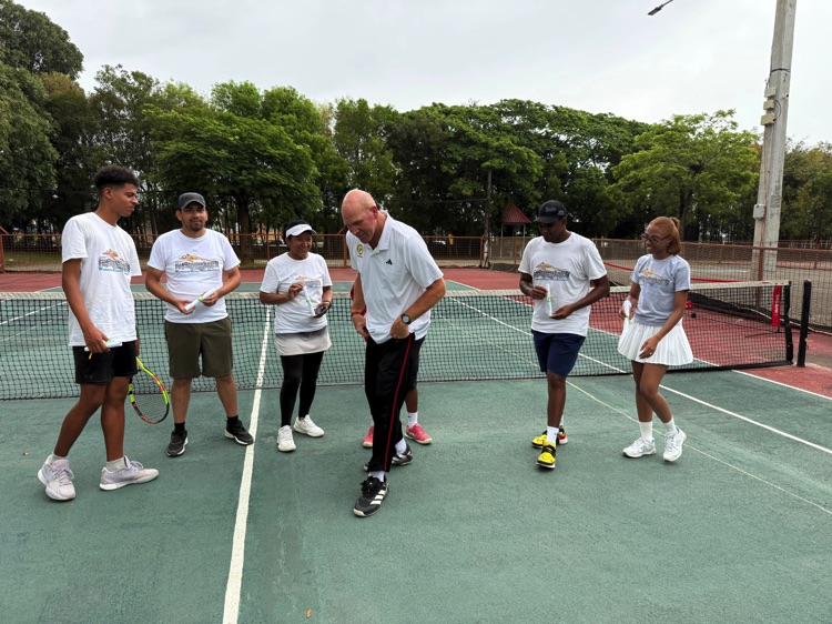 Participantes practican juntos durante una clase de tenis.