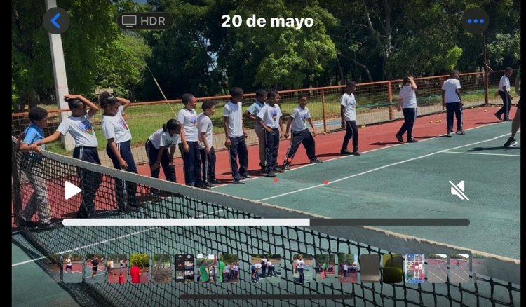 Participantes forman una fila junto a la red durante una actividad de tenis.