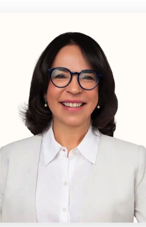 Retrato de una mujer con gafas y chaqueta blanca.